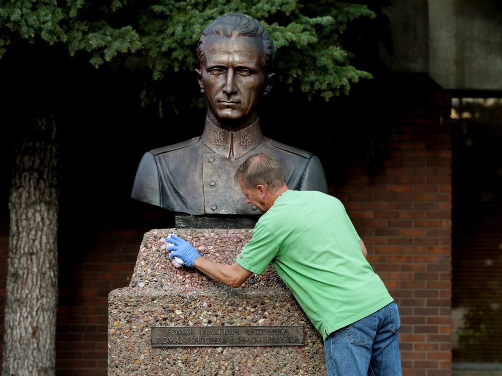 A volunteer scrubs spray paint off the Roman Shukhevych statue at the Ukrainian Youth Unity Complex, 9615 153 Ave., in Edmonton on Aug. 10, 2021. Progress Alberta director Duncan Kinney is accused of vandalizing the statue with anti-Nazi graffiti.