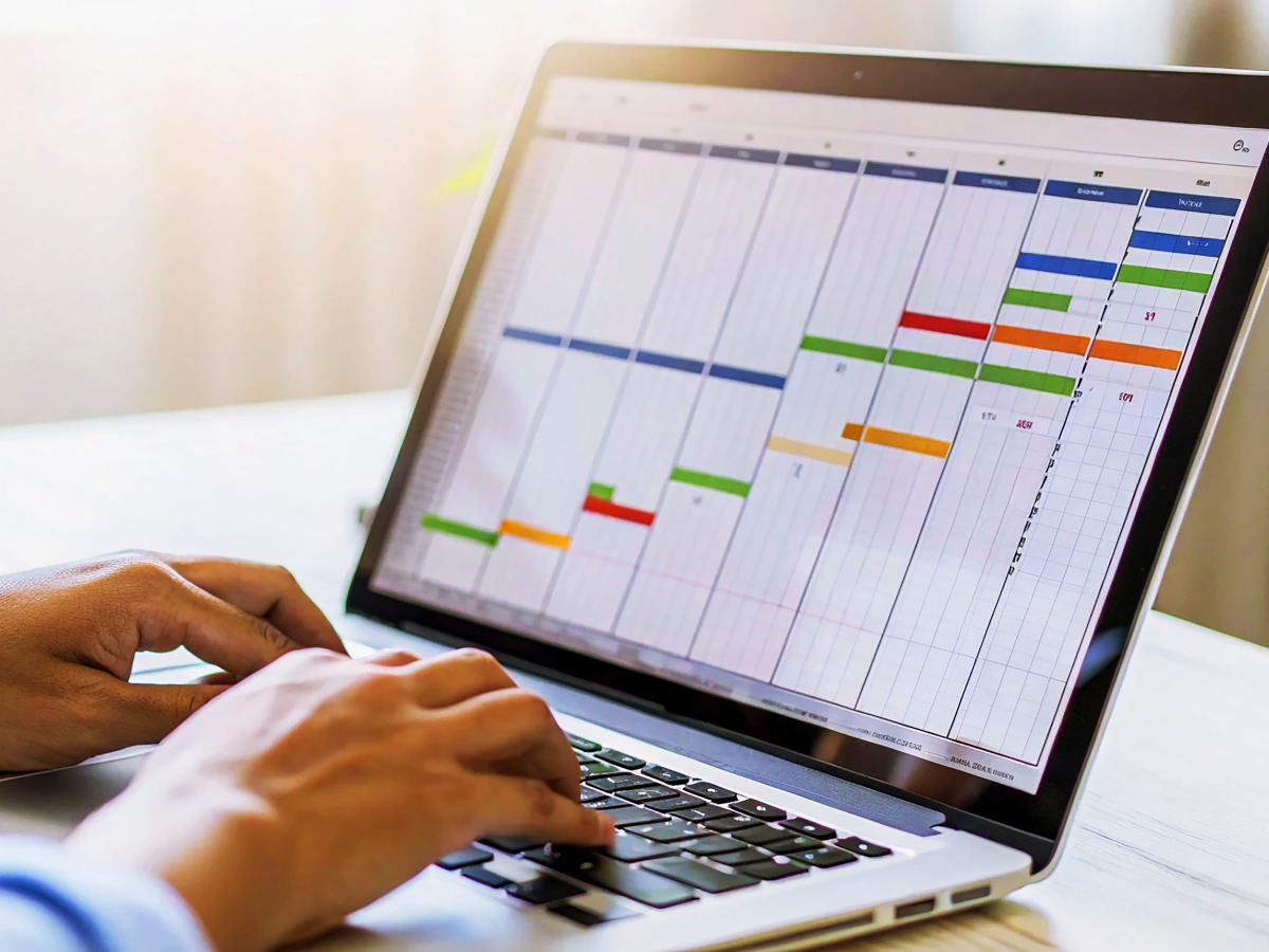 Business person typing on laptop with a colorful gantt chart for project management and planning