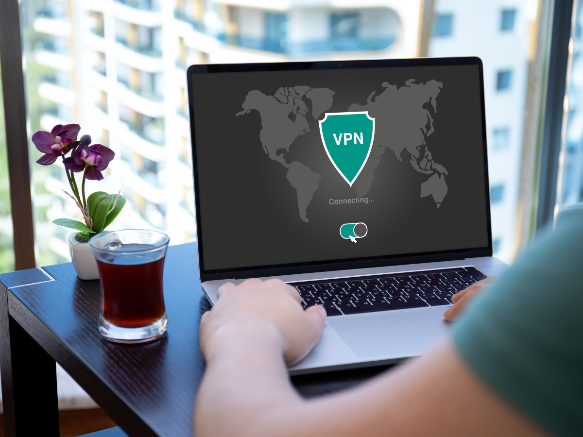 man uses app vpn on screen computer laptop in cafe