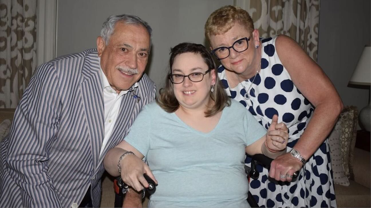 A father, daughter, and mother pose for a photo, smiling.