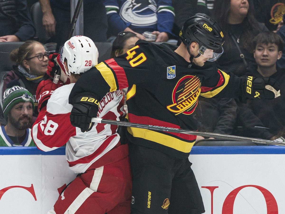Elias Pettersson hits Nate Danielson of the Detroit Red Wings along the boards during the first period.