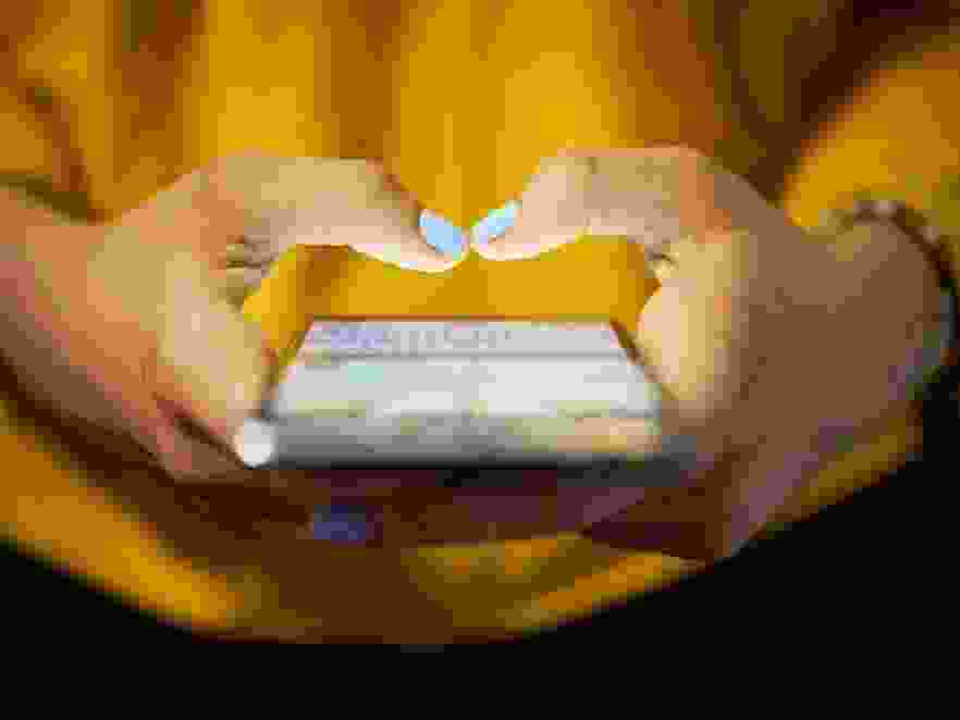Young woman using cell phone to send text message on social network at night.