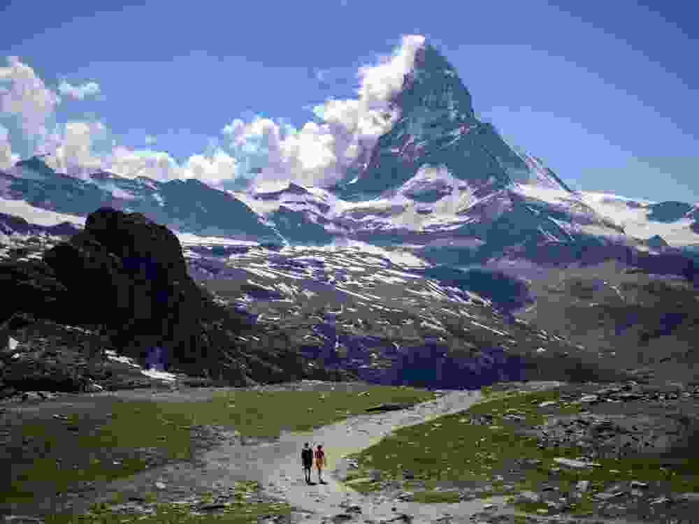 A couple of tourists walk on a trail below the Matterhorn mountain in Zermatt on June 30, 2015. 
