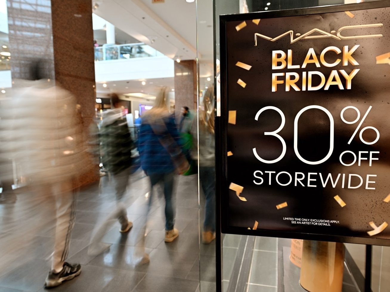 Shoppers walk past a Black Friday sale banner.