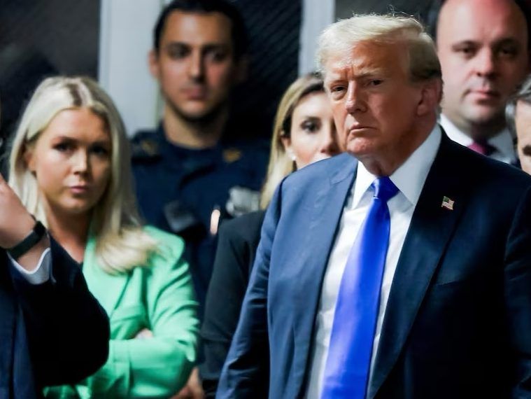 Karoline Leavitt, left, and Alina Habba, partly hidden, standing behind Donald Trump as he arrives for his hush money trial at Manhattan Criminal Court on May 30, 2024 in New York City.