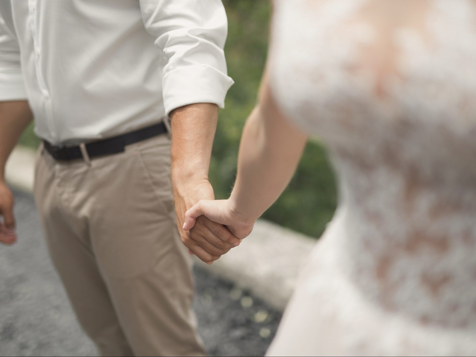 Closeup of groom and brides arms. holding hands.