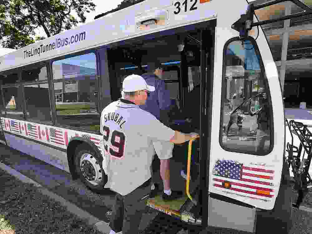 All aboard! Detroit Tigers fans board the new privately operated tunnel bus on Bruce Avenue near Riverside Drive West in Windsor on Wednesday, Oct. 8, 2025. The cross-border service is called The Linq and picks up passengers on the hour.