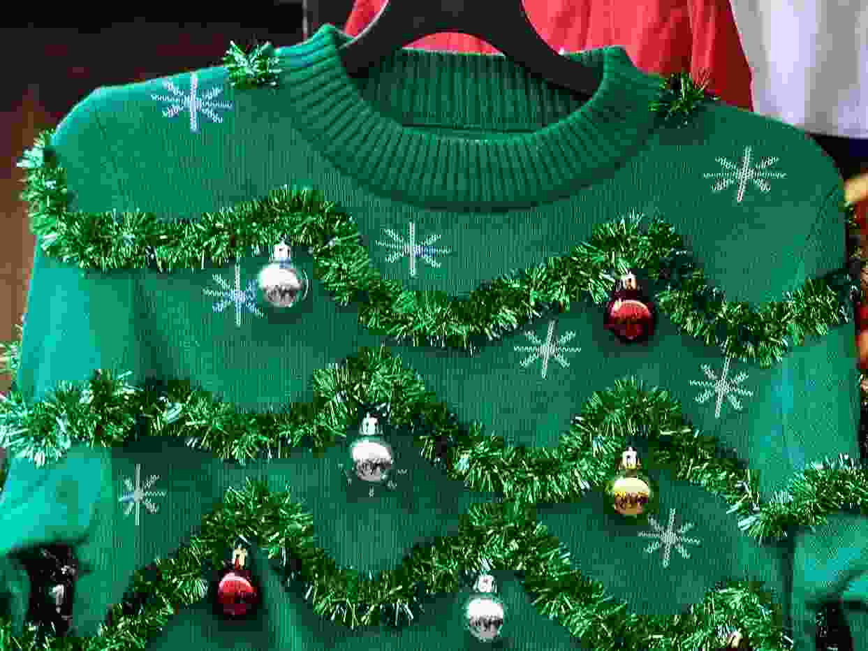 Green Christmas sweater decorated with colourful mini ball ornaments and green tinsel.