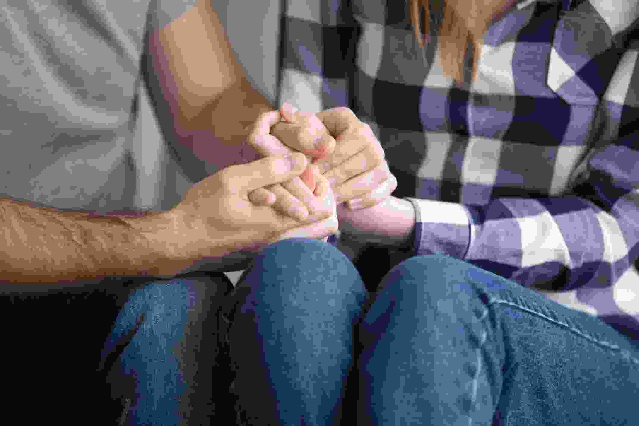 A couple holding hands while in relationship therapy.