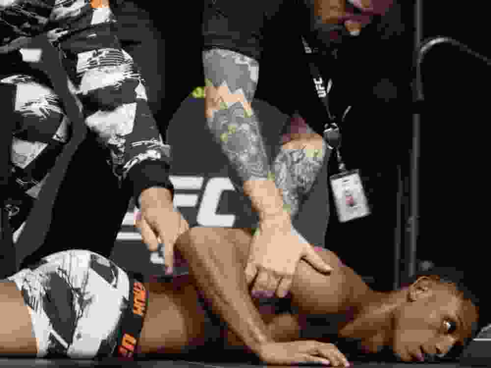 UFC fighter Cameron Smotherman lies on the stage after weighing in.