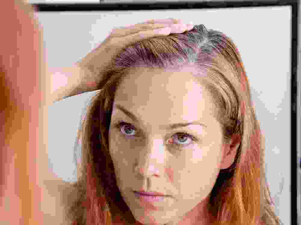 Gray haired woman looking at reflection in morror