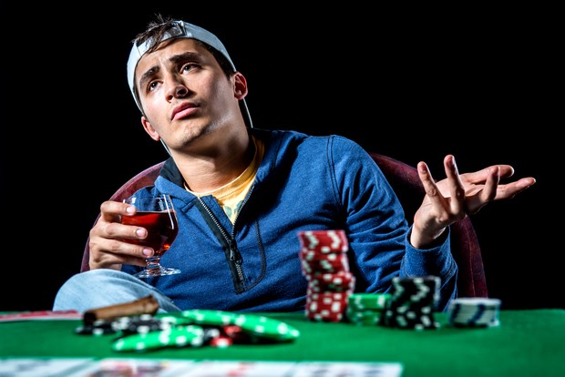 Young gambler holding glass of cognac.