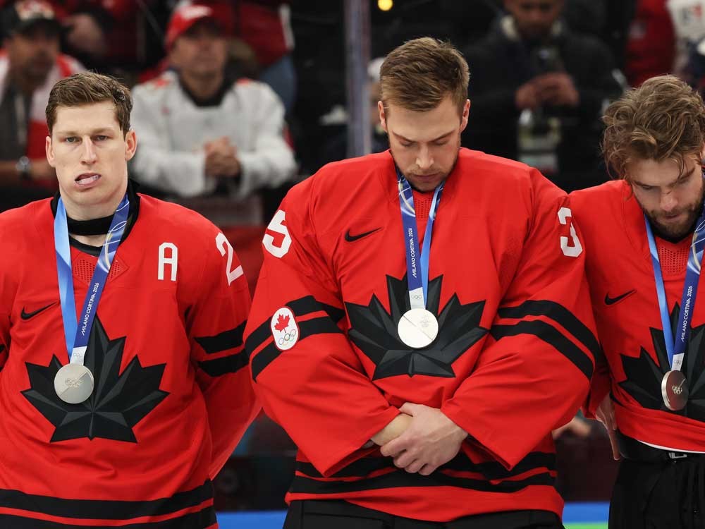 Silver medalists Nathan MacKinnon, left, Darcy Kuemper, centre, and Brandon Hagel of Team Canada react during the medal ceremony for Men's Ice Hockey following the Men's Gold Medal match between Canada and the United States of the Milano Cortina 2026 Winter Olympic Games at Milano Santagiulia Ice Hockey Arena on Feb. 22, 2026 in Milan, Italy.