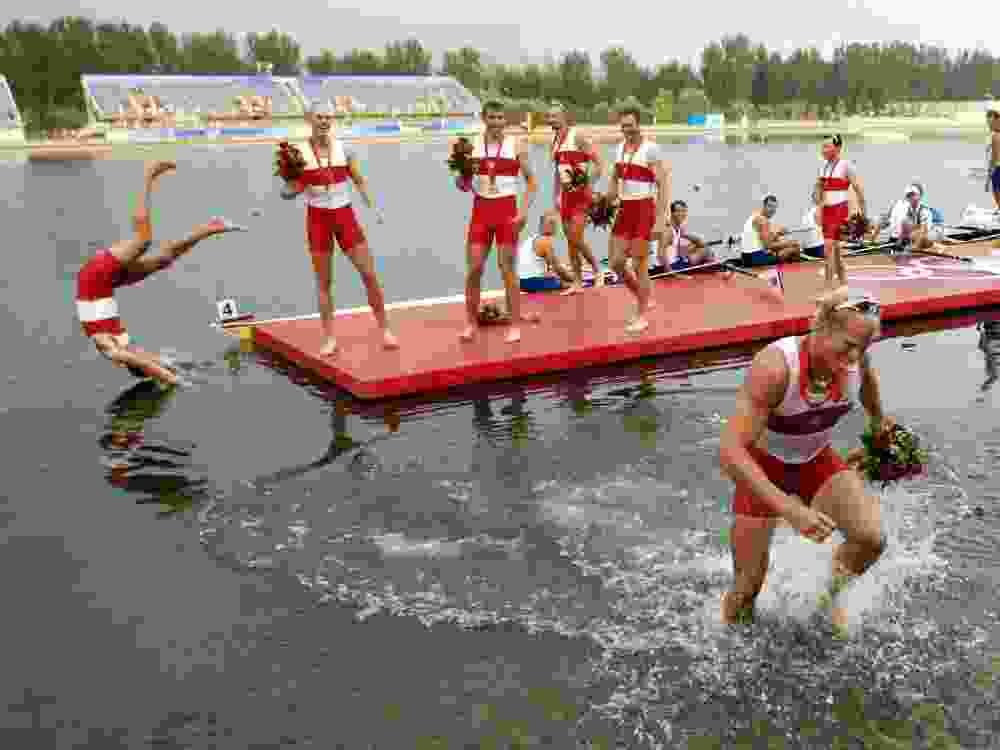 Canada's Adam Kreek walks out of the water with his gold medal as his teammates celebrate after the men's eight rowing competition at the Beijing 2008 Olympic Games.