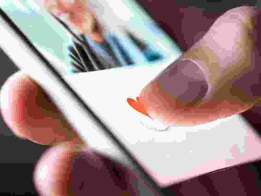 Man giving a like to photo on social media or swiping on online dating app. Finger pushing heart icon on screen in smartphone application.