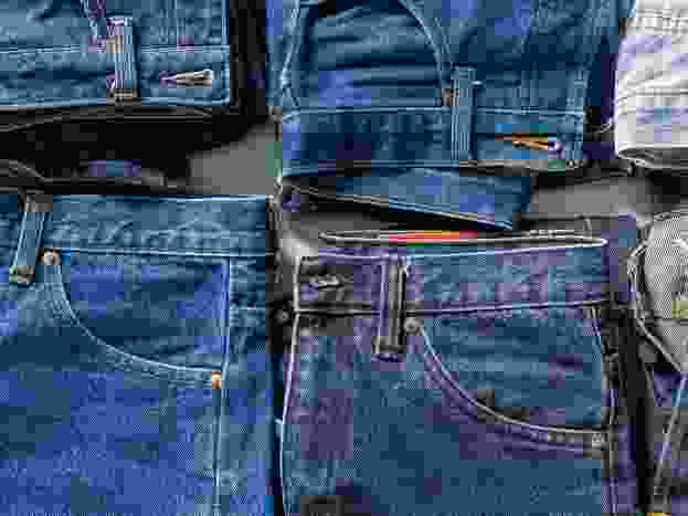 top view of folded jeans,Blue jeans on a stack of jeans . Top view of various denim fabrics on white background. Several long jeans