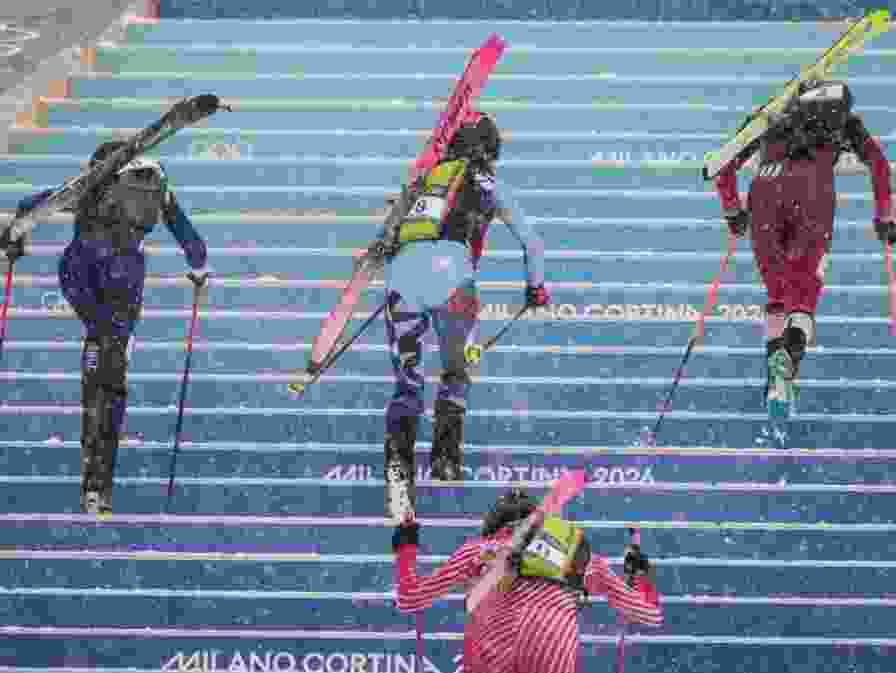 Competitors race uphill in a women's sprint ski mountaineering heat during the Milano Cortina 2026 Winter Olympic Games.