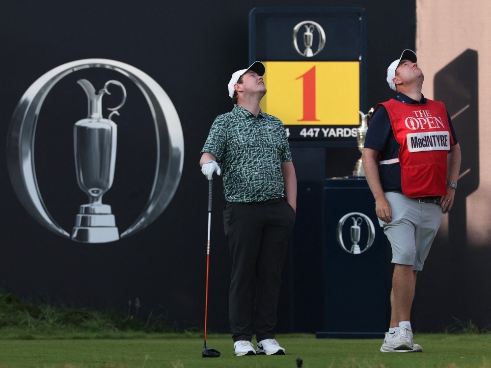 Scotland's Robert MacIntyre and his caddie Mike Burrows look at a drone flying above the 1st tee on day one of the 154th Open Golf championship at Royal Birkdale.
