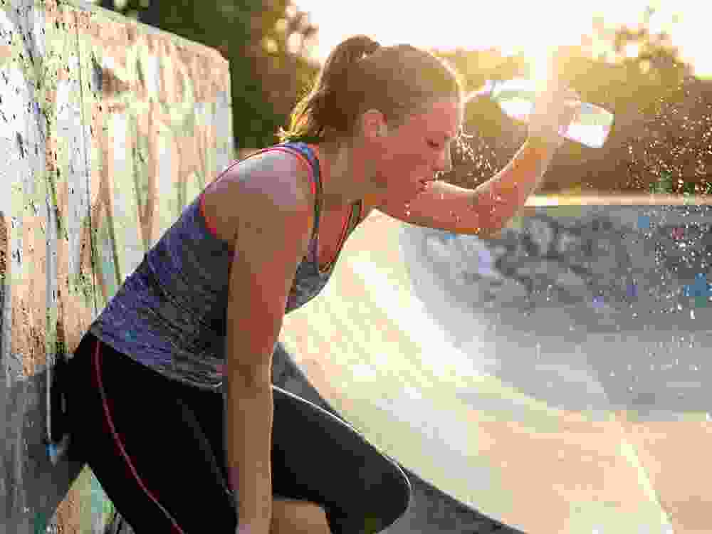 Heat stroke high temperature heatwave woman cools with water after outdoor workout