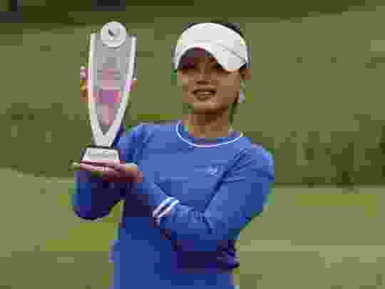 Teenage golfer Jessica Bang holds a trophy.