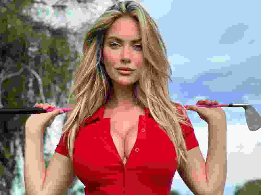 Golf influencer Paige Spiranac poses for a photo holding a golf club.