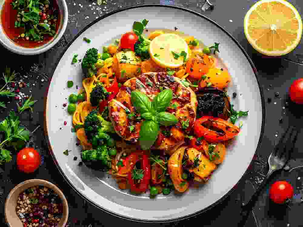 A plate of grilled chicken and vegetables with herbs