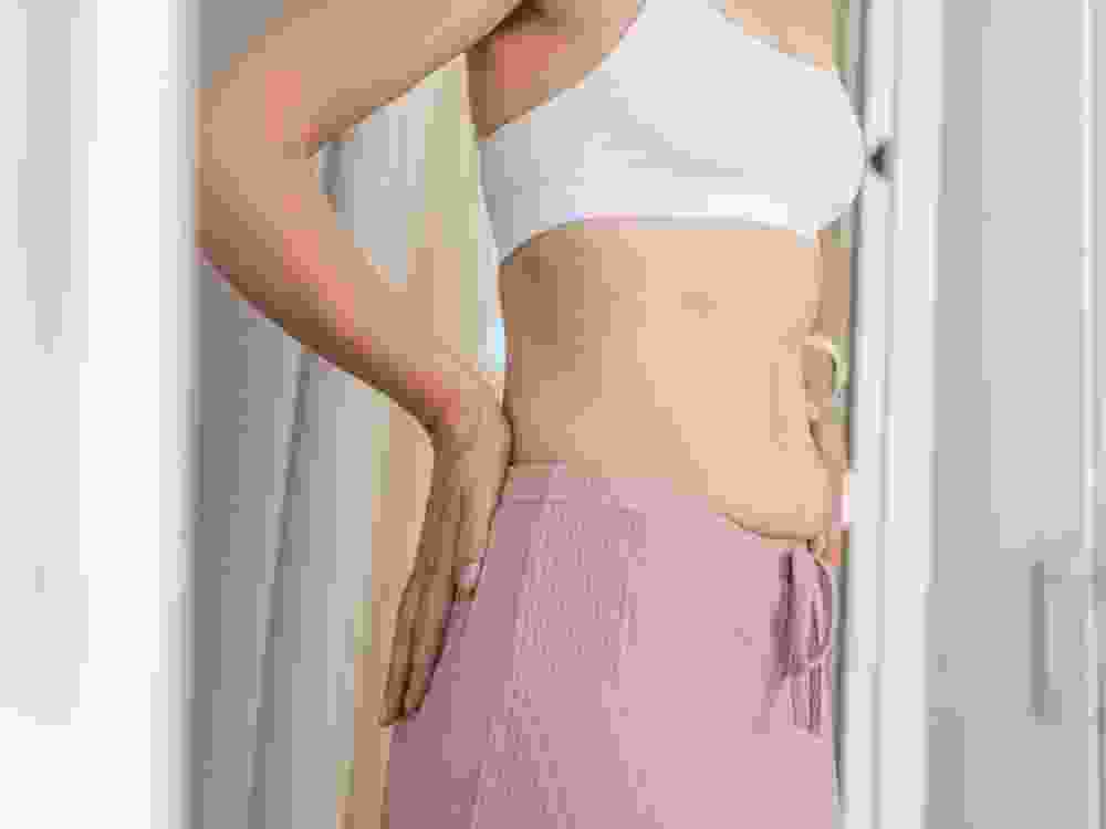 Woman showing loose stomach skin and belly creases after weight loss, reflecting on body changes, stretch mark appearance, and skin health issues related to aging