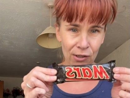 Woman holding a Mars bar from 1991 that she found while cleaning a hoarder's house.
