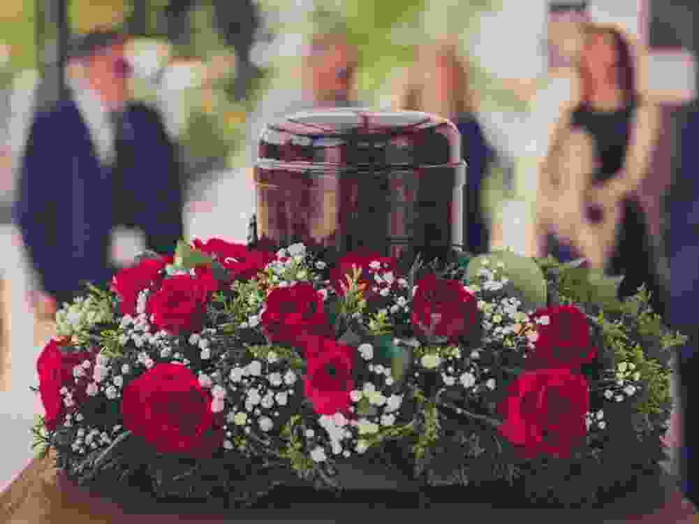 Funerary urn with ashes of dead and flowers at funeral