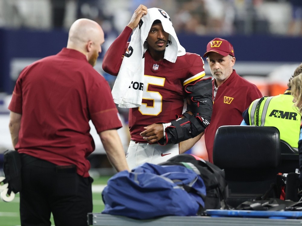 Jayden Daniels of the Washington Commanders looks on before being carted off the field after sustaining an injury against the Dallas Cowboys.