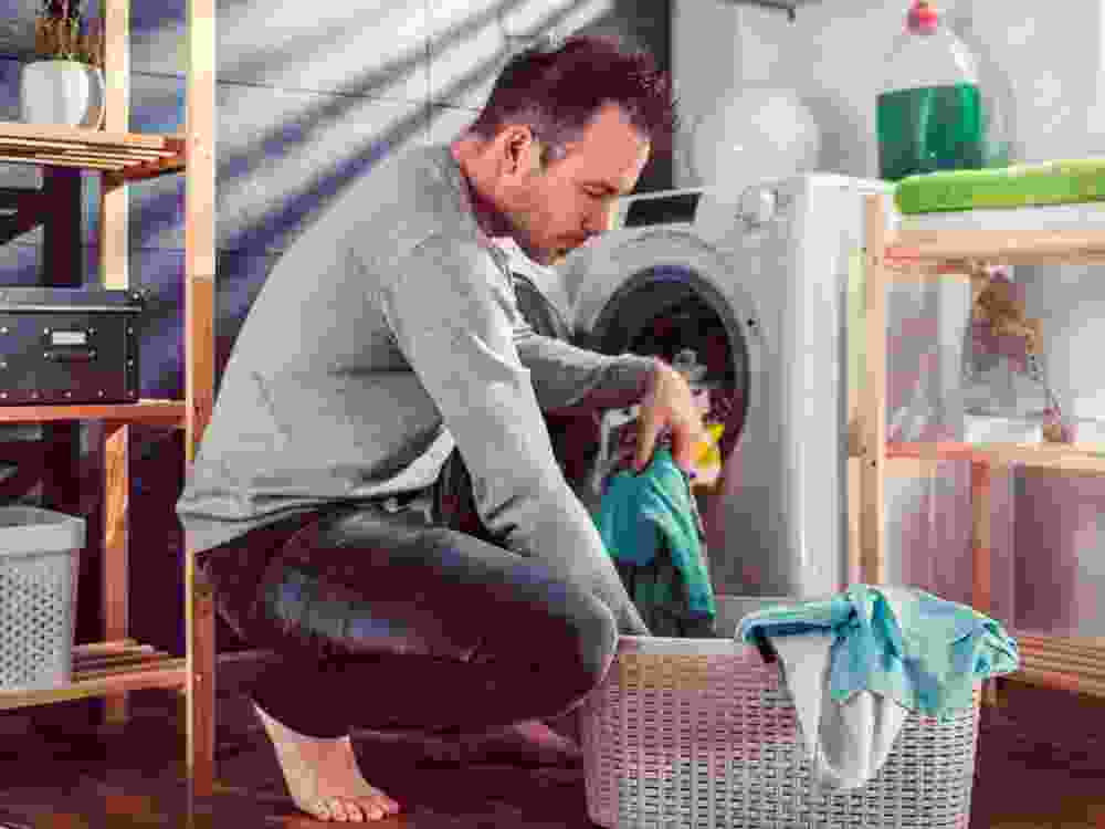 A man puts clothes into a washing machine