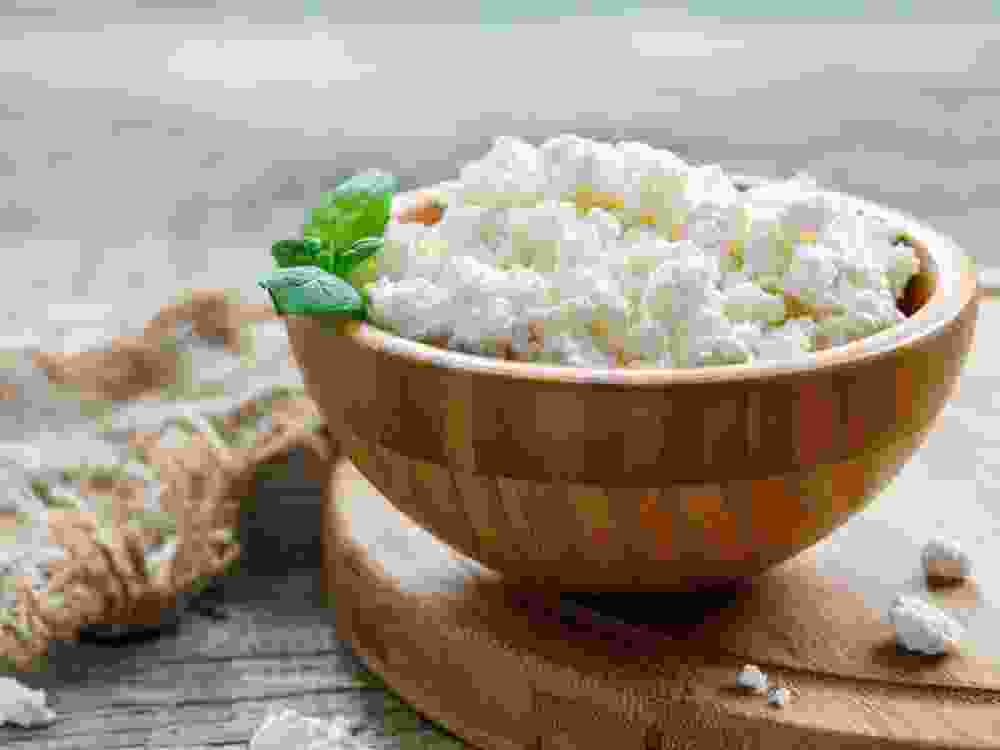 Fresh cottage cheese and mint in a wooden bowl.