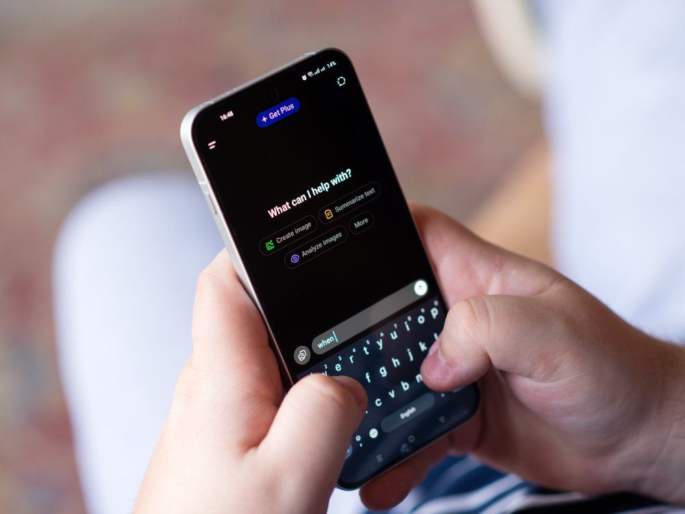 Kyiv, Ukraine. April 3, 2026. Close-up of a person's hands typing on a smartphone using an AI chatbot interface with "What can I help with?" text.