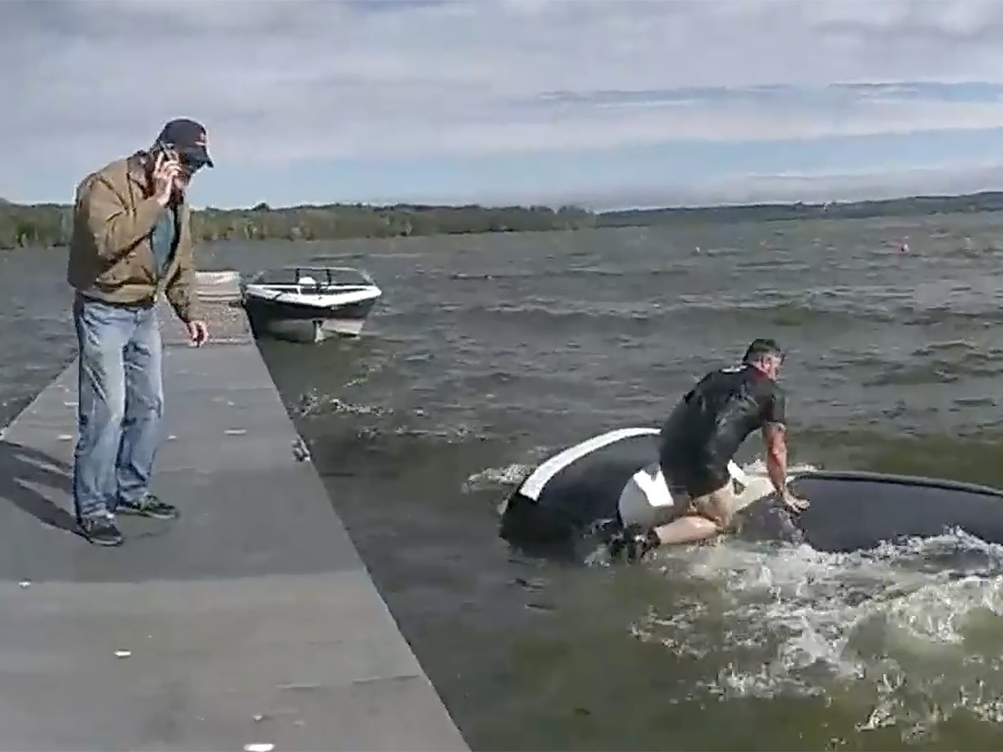 A New York State trooper is seen atop a sinking vehicle in a lake in upstate New York.