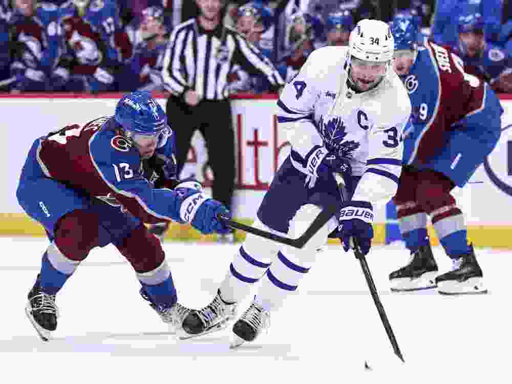 T.J. Hughes of the Colorado Avalanche and Auston Matthews of the Toronto Maple Leafs compete for the puck.