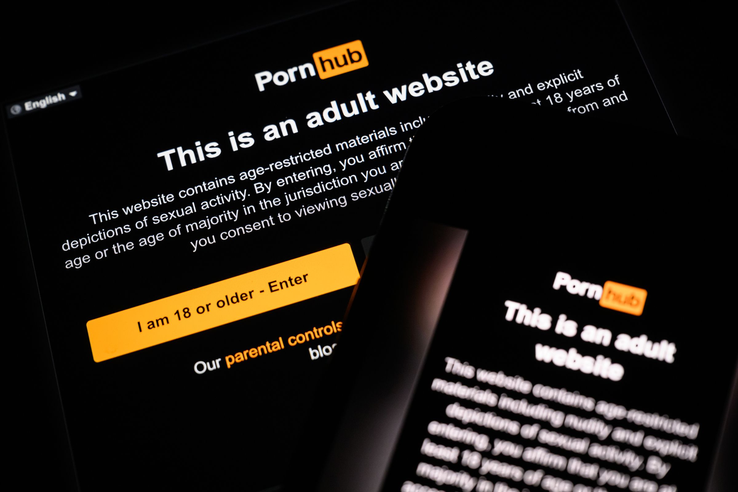 In this photo illustration, the age-restriction warning screen of the website Pornhub is displayed on two digital screens.