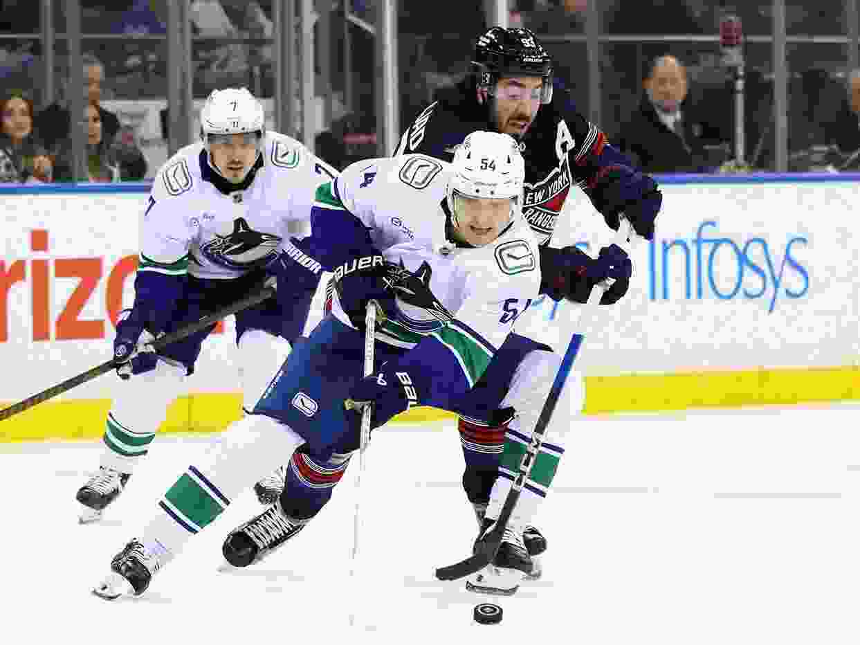 Mika Zibanejad of the New York Rangers checks Aatu Räty of the Vancouver Canucks.