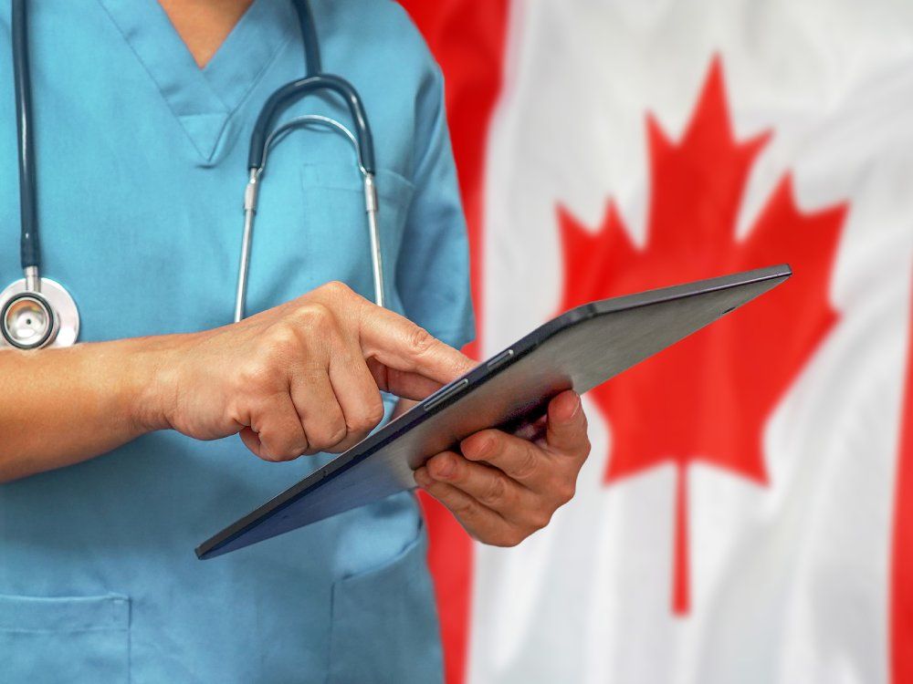 Surgeon or doctor using a digital tablet on the background of the Canada flag.