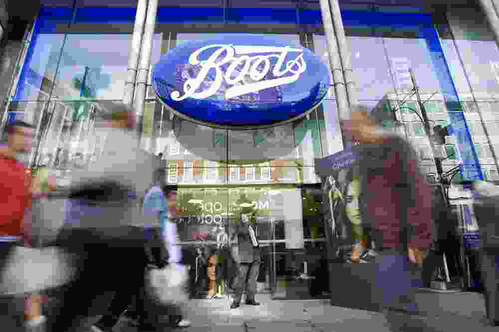 Passers-by walk in front of a Boots Store on Oxford Street in London.