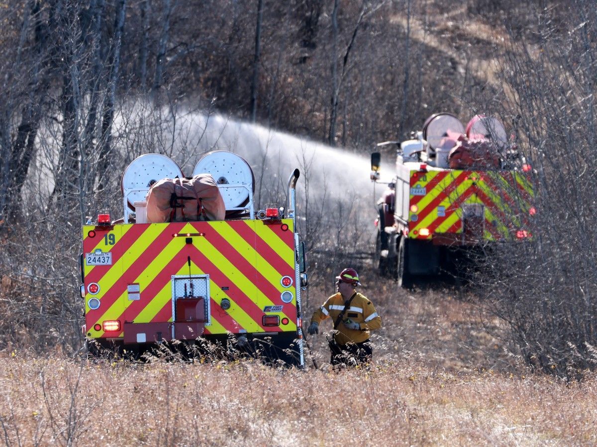 Canadian Forces fire trucks extinguish hot spots on the edge of Canadian Forces Base Wainwright on October 18, 2026. The blaze initially spread quickly, killing several soldiers and injured dozens more during a training exercise on Saturday afternoon.